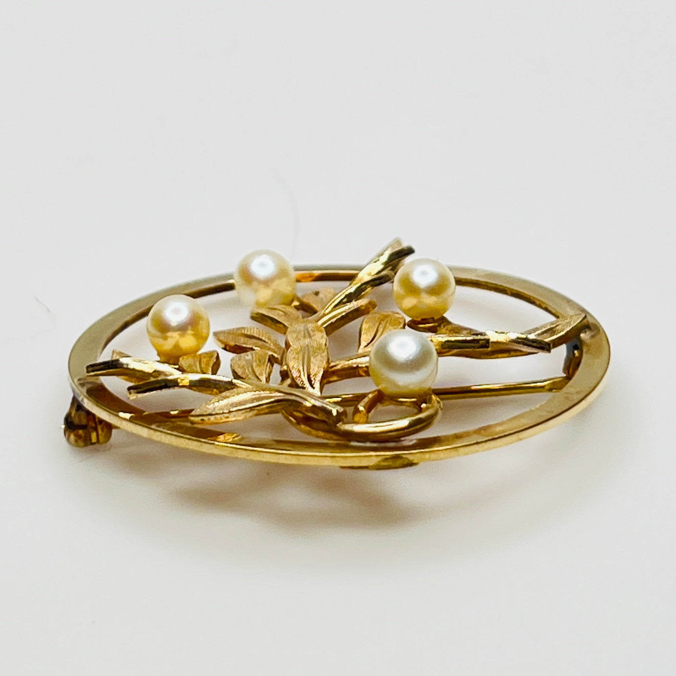 Close-up of brooch with textured gold leaves and five pearls