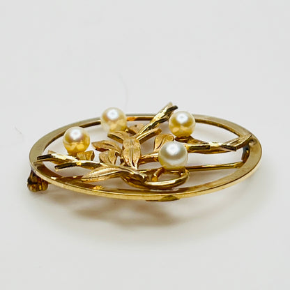 Close-up of brooch with textured gold leaves and five pearls