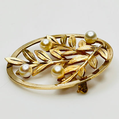 Close-up of brooch with textured gold leaves and five pearls