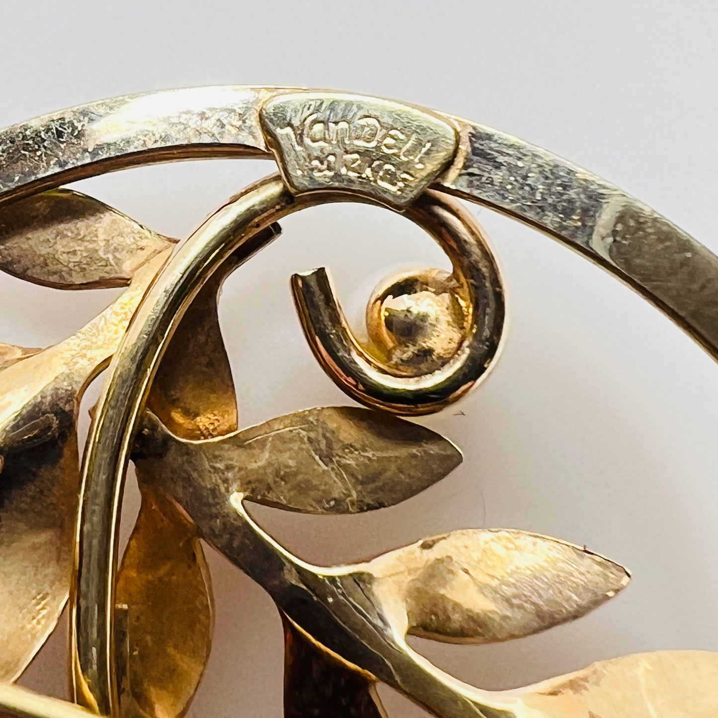 Close-up of brooch with textured gold leaves and five pearls
