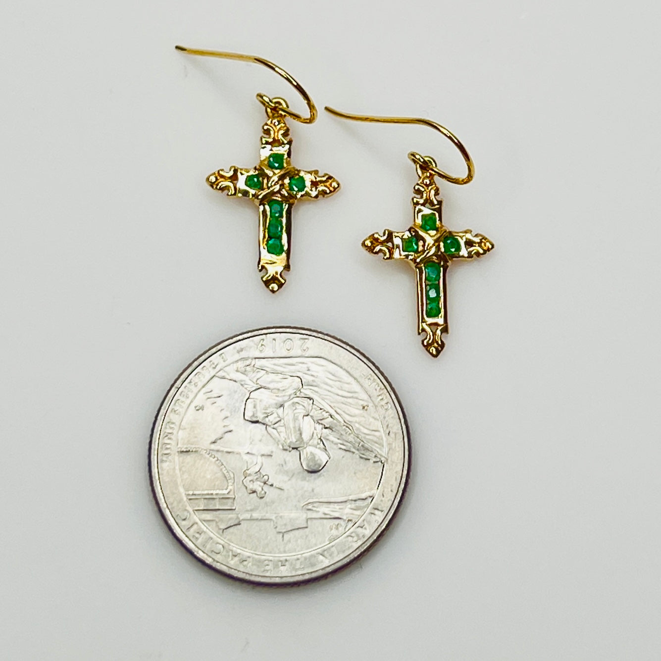 Close up of emerald gemstone cross earrings