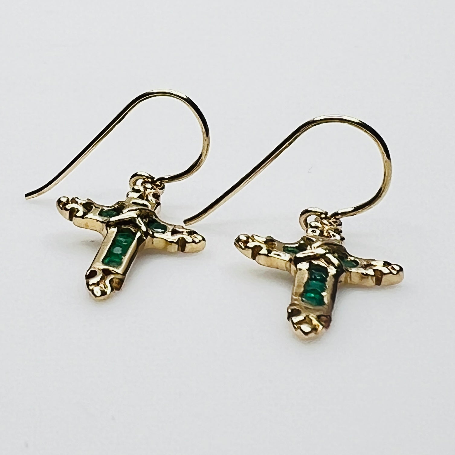 Close up of emerald gemstone cross earrings