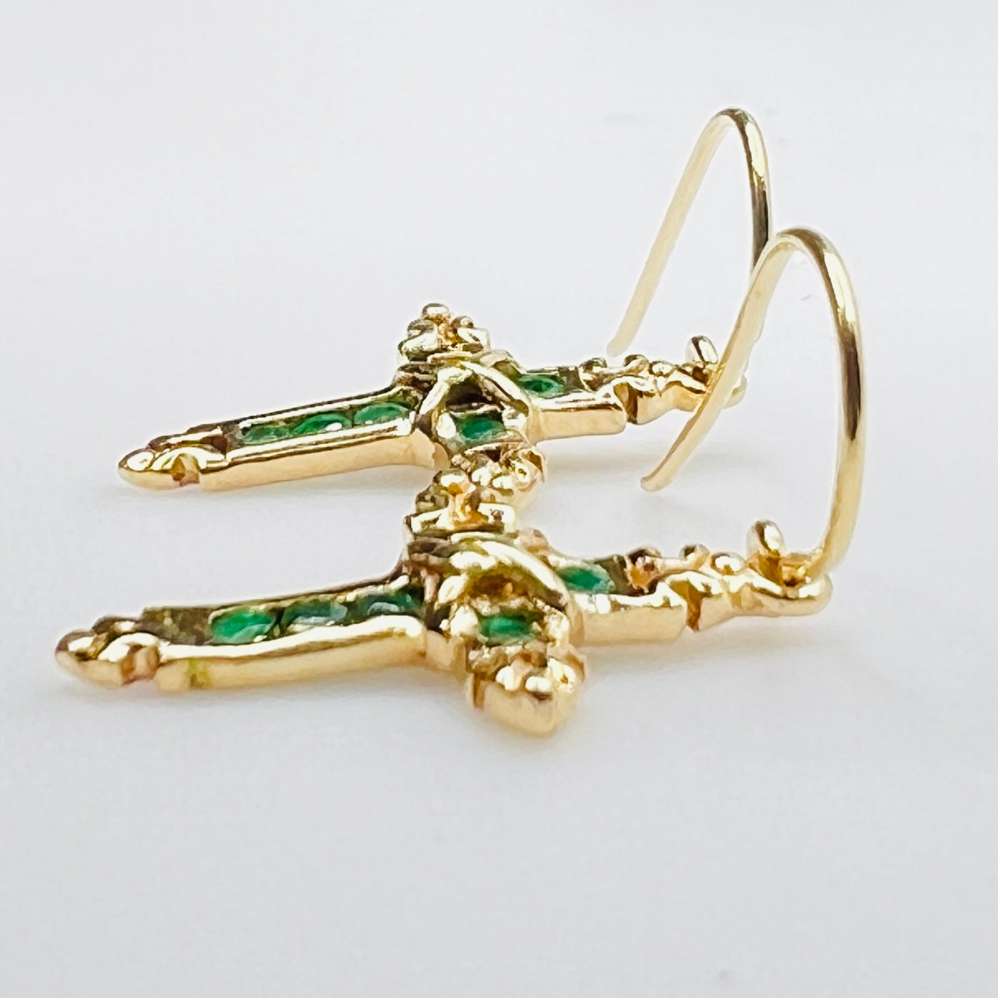Close up of emerald gemstone cross earrings