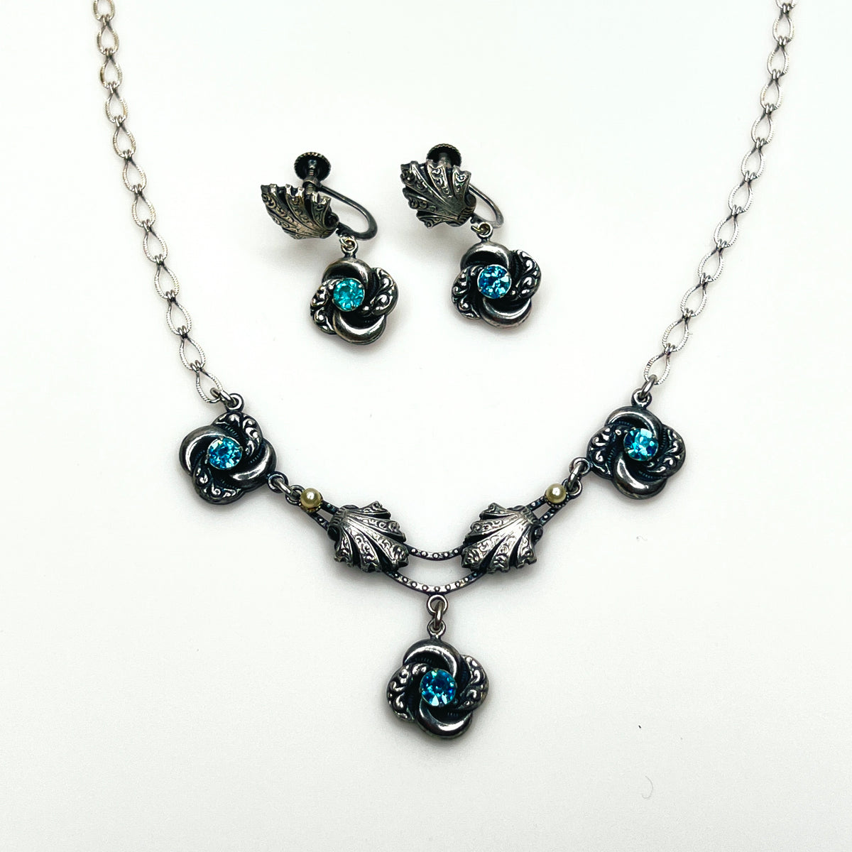 Vintage silver-tone Art Nouveau Revival necklace and screw-back earrings with aqua rhinestones and ornate floral details.