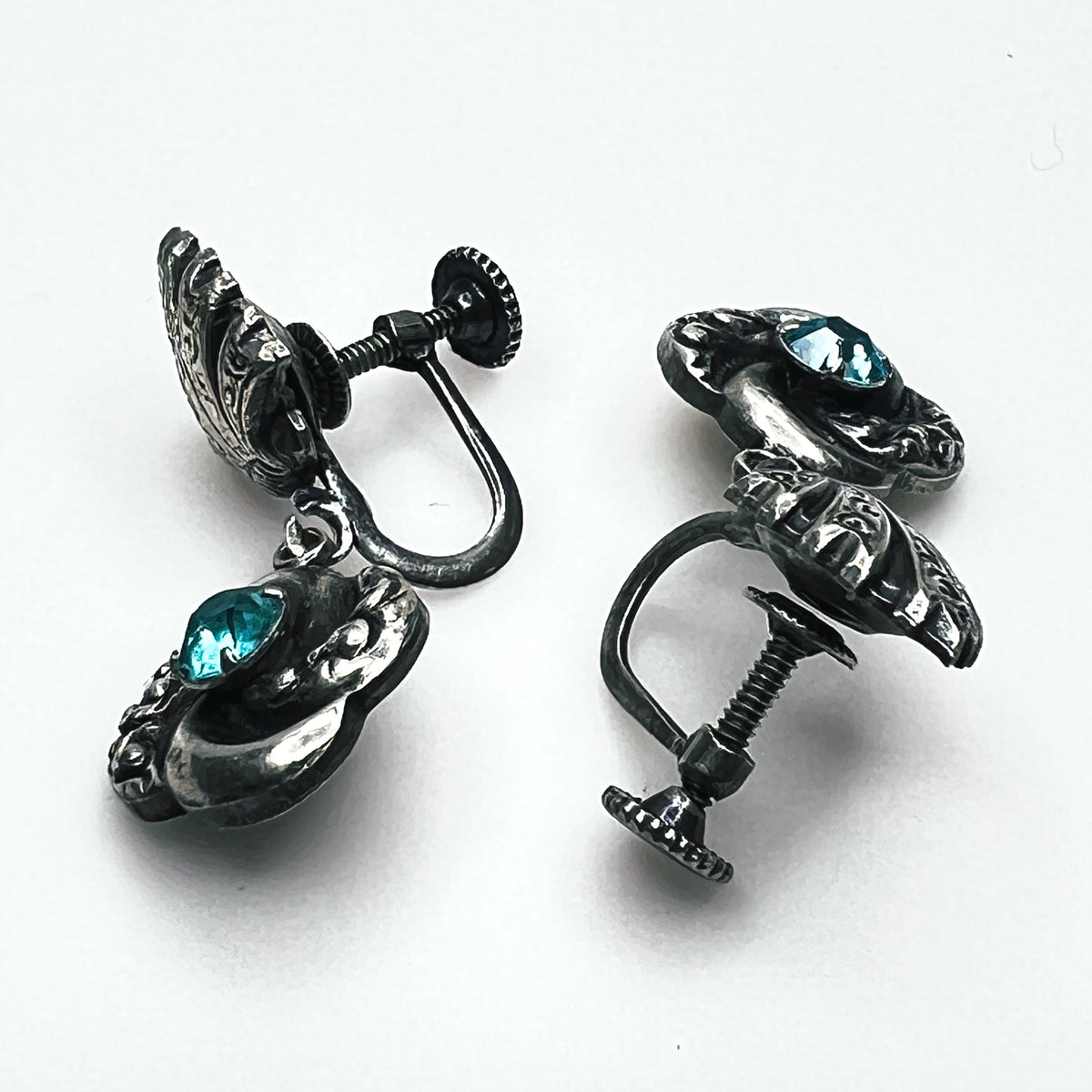 Side view of vintage screw-back floral earrings showing adjustable screw fittings and metal construction.