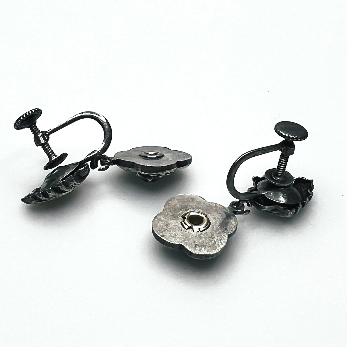 Side view of vintage screw-back floral earrings showing adjustable screw fittings and metal construction.
