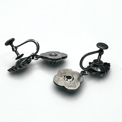 Side view of vintage screw-back floral earrings showing adjustable screw fittings and metal construction.