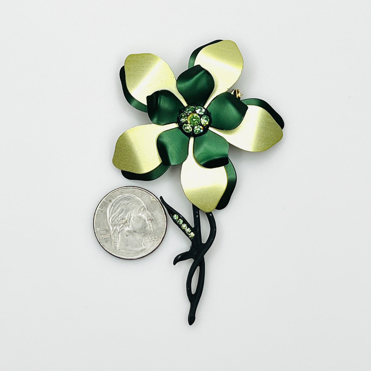 Large vintage green enamel rhinestone flower brooch beside a quarter showing its statement size and dimensional floral design.