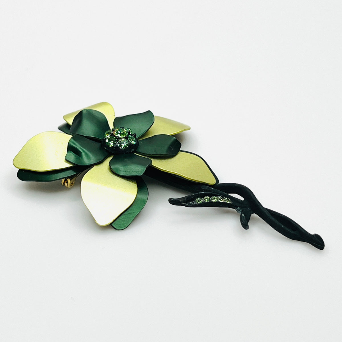 Side view of vintage 1970s green enamel flower brooch showing curved layered petals, rhinestone center, and dimensional construction.