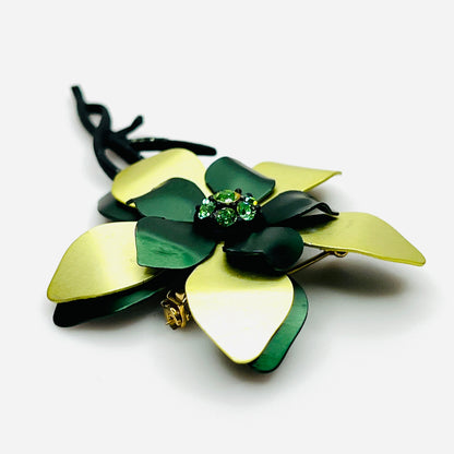 Side view of vintage 1970s green enamel flower brooch showing curved layered petals, rhinestone center, and dimensional construction.