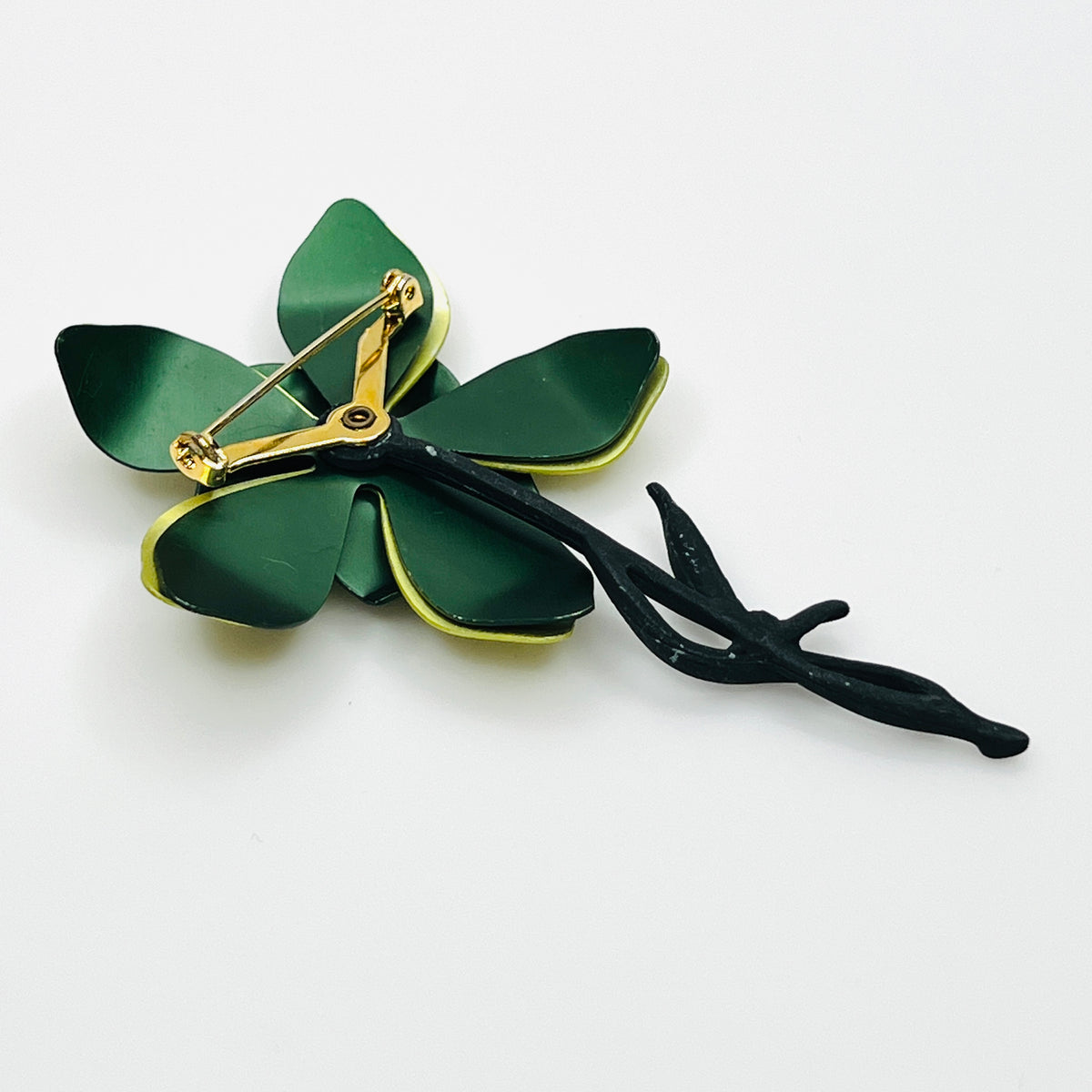 Side view of vintage 1970s green enamel flower brooch showing curved layered petals, rhinestone center, and dimensional construction.