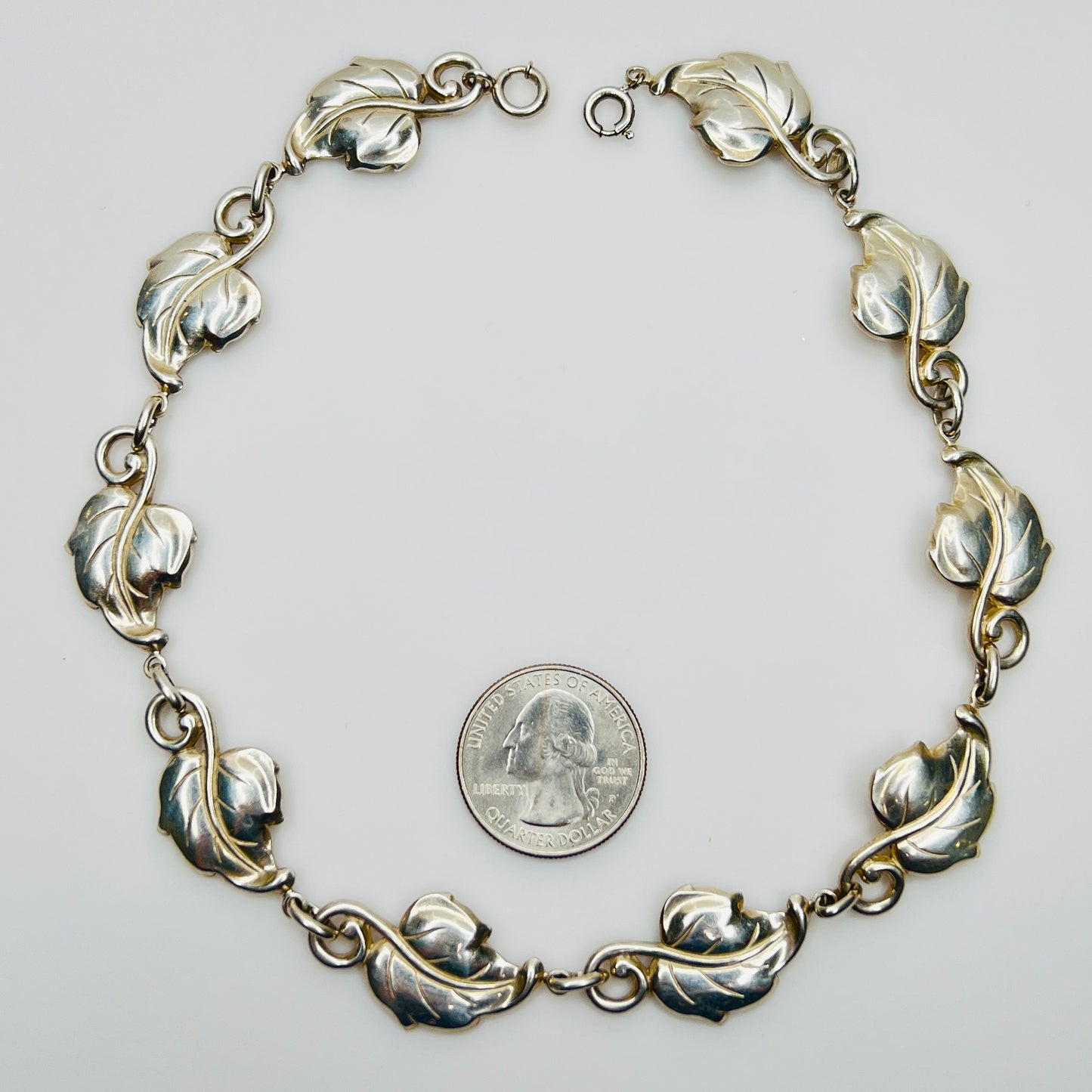 Linked leaf motif sterling necklace flat lay with coin for scale