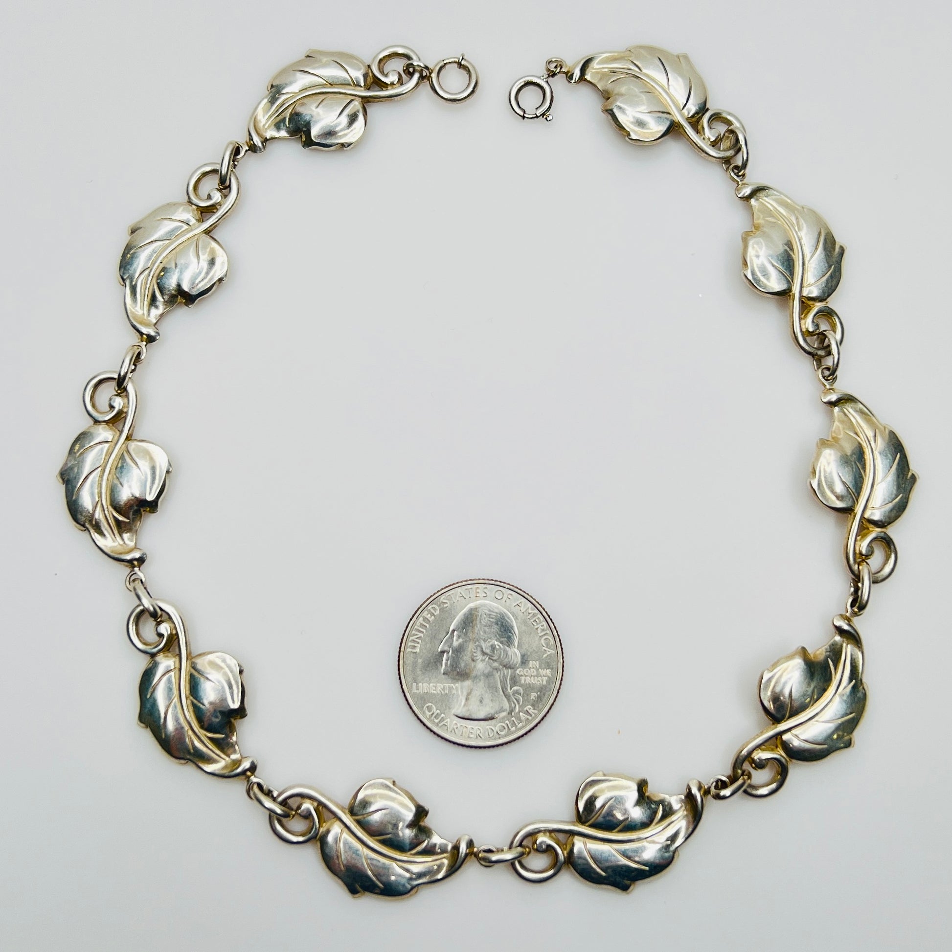 Linked leaf motif sterling necklace flat lay with coin for scale