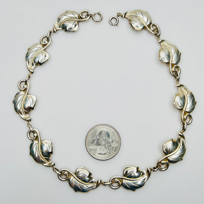 Linked leaf motif sterling necklace flat lay with coin for scale
