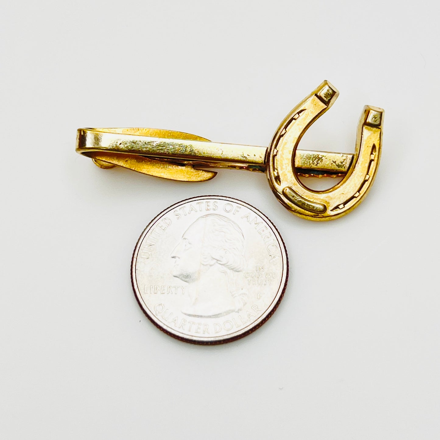 Signed Hickok horseshoe tie clip shown beside quarter for size reference