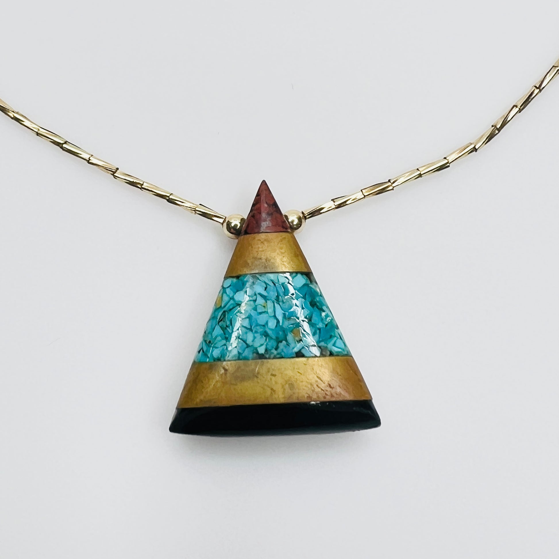 Close-up turquoise chip inlay geometric pendant gold accents