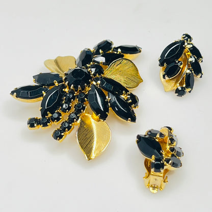 Close-up of Weiss signed black rhinestone clip-on earrings with gold leaf accents
