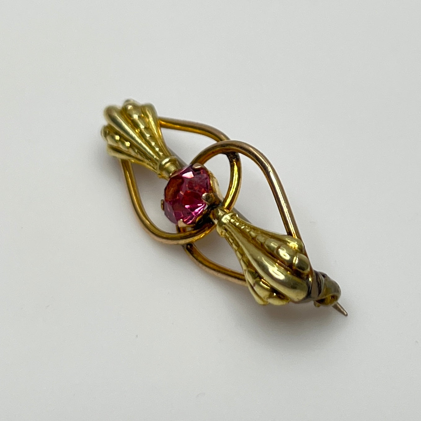 Vintage estate brooch with scroll design and prong-set pink glass stone