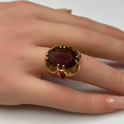 Bold 1970s gold-plated ring with large oval purple stone on hand