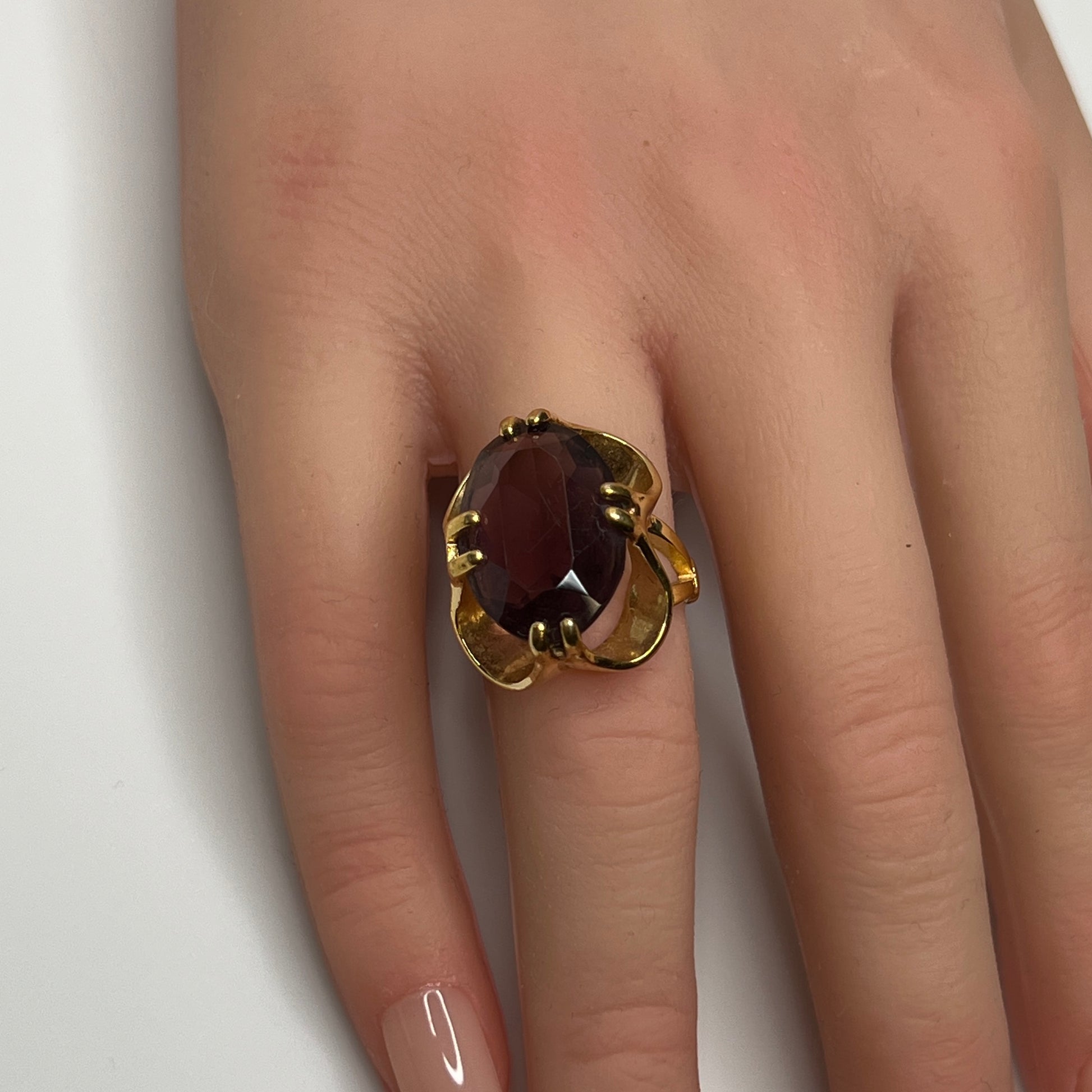 Bold 1970s gold-plated ring with large oval purple stone on hand