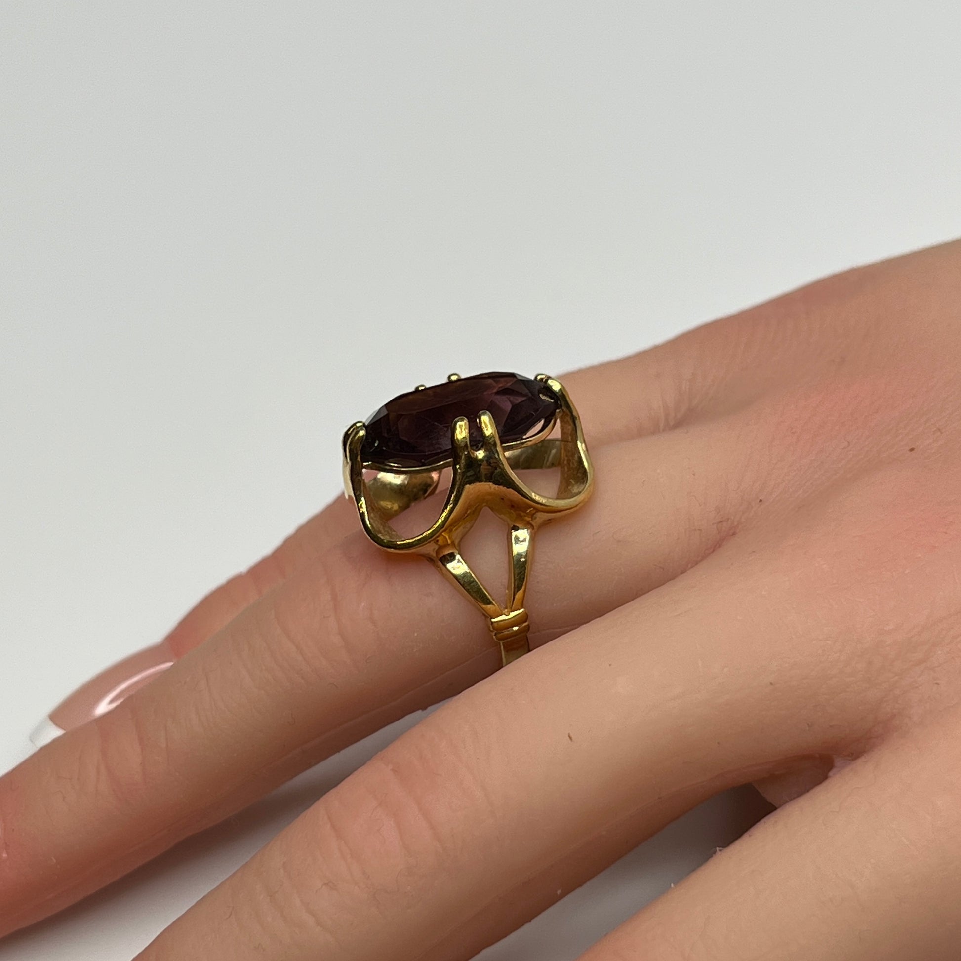 Bold 1970s gold-plated ring with large oval purple stone on hand