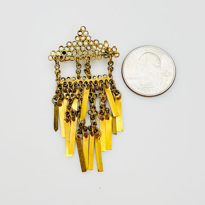 Vintage brass Art Deco tassel brooch beside quarter for scale