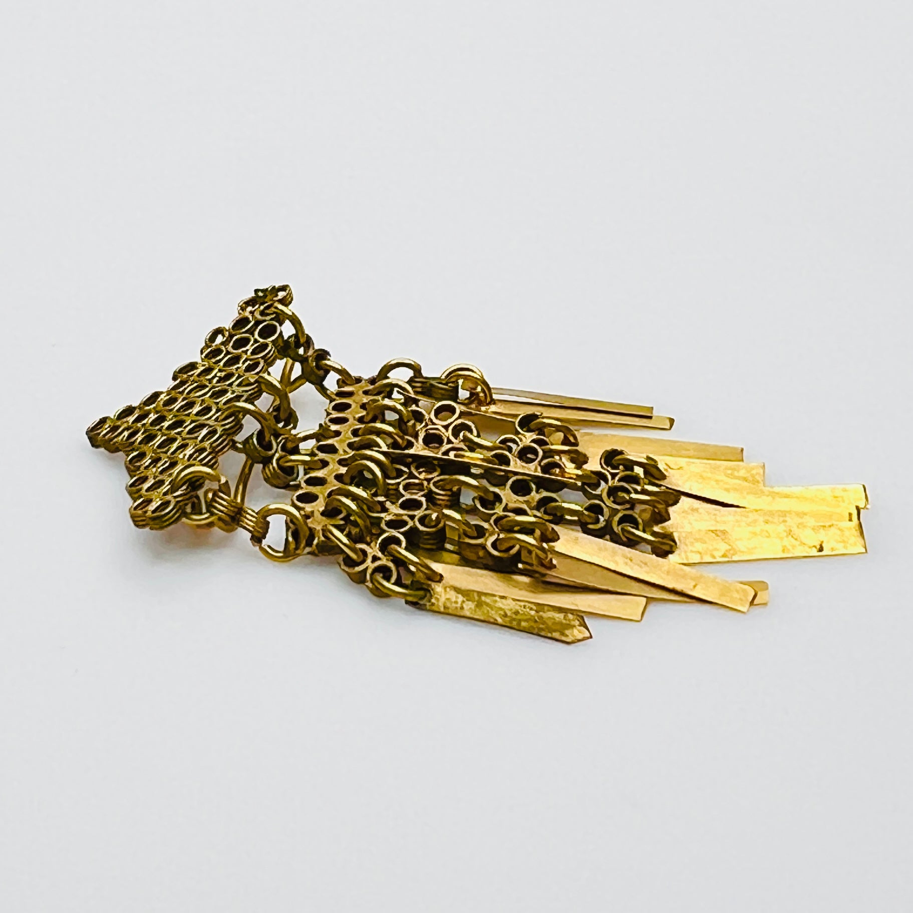 Side profile of 1920s brass fringe brooch with articulated tassels