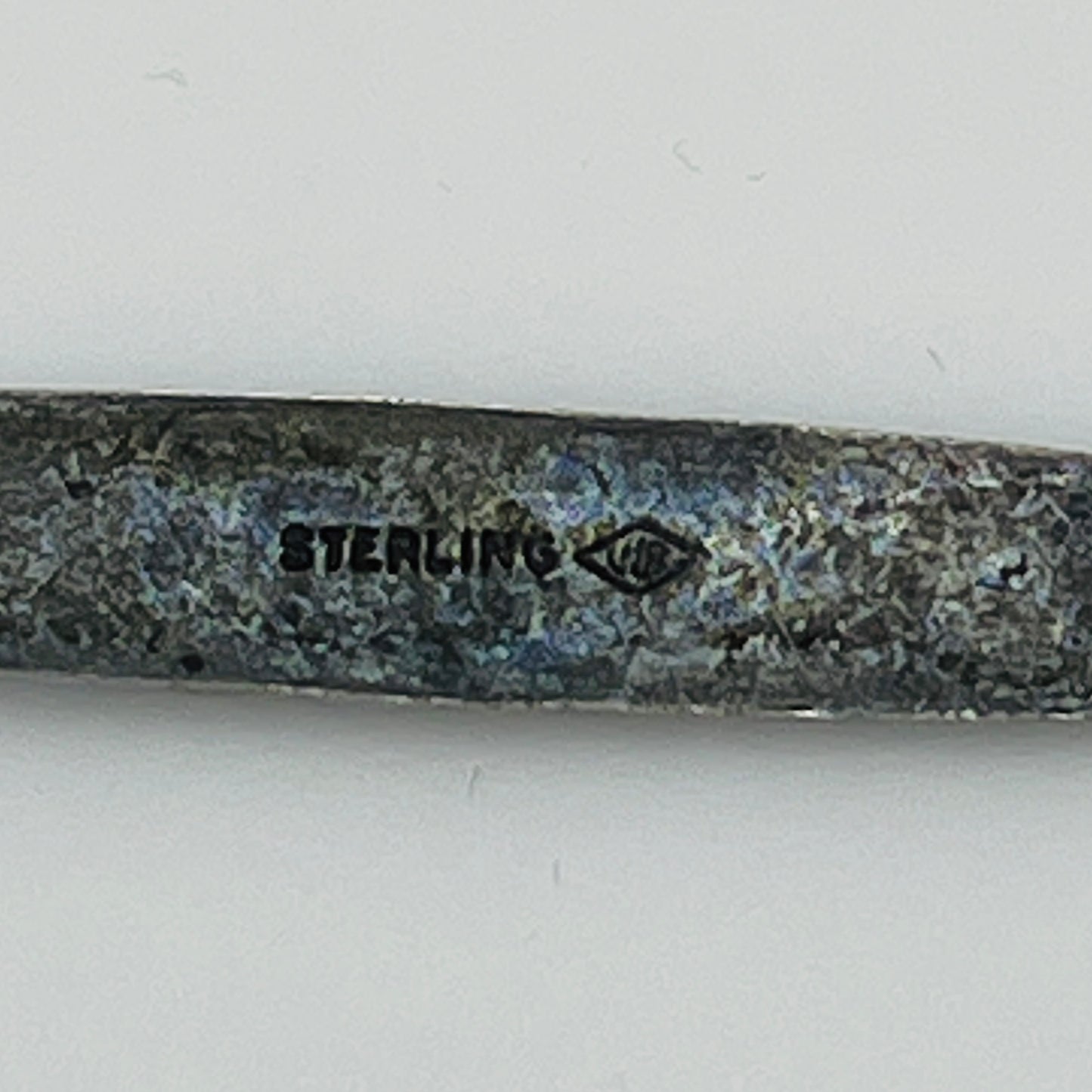 Close-up of “STERLING” stamp with maker’s mark on reverse