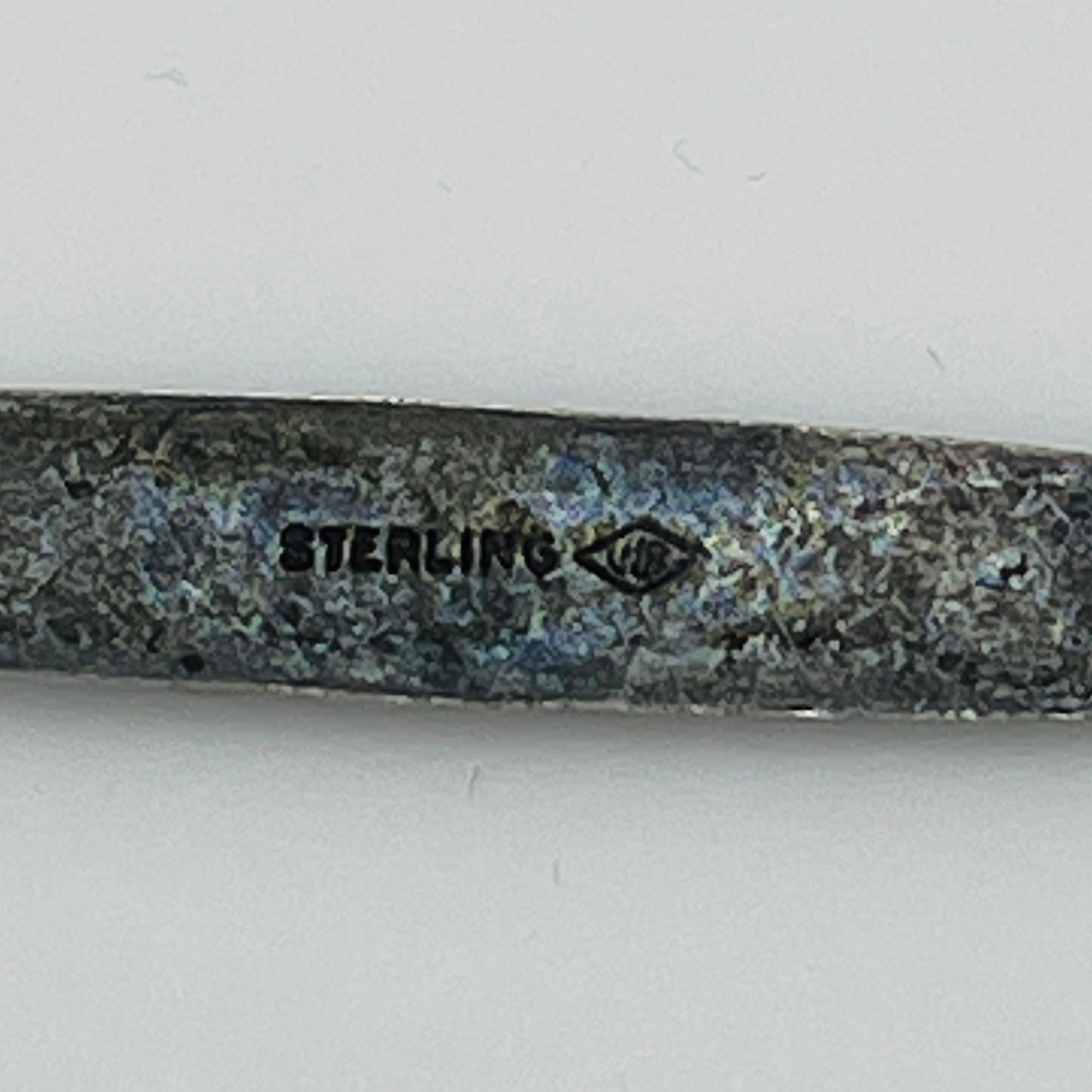 Close-up of “STERLING” stamp with maker’s mark on reverse