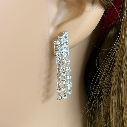 Close-up of silver-tone fringe earrings with prong-set crystals