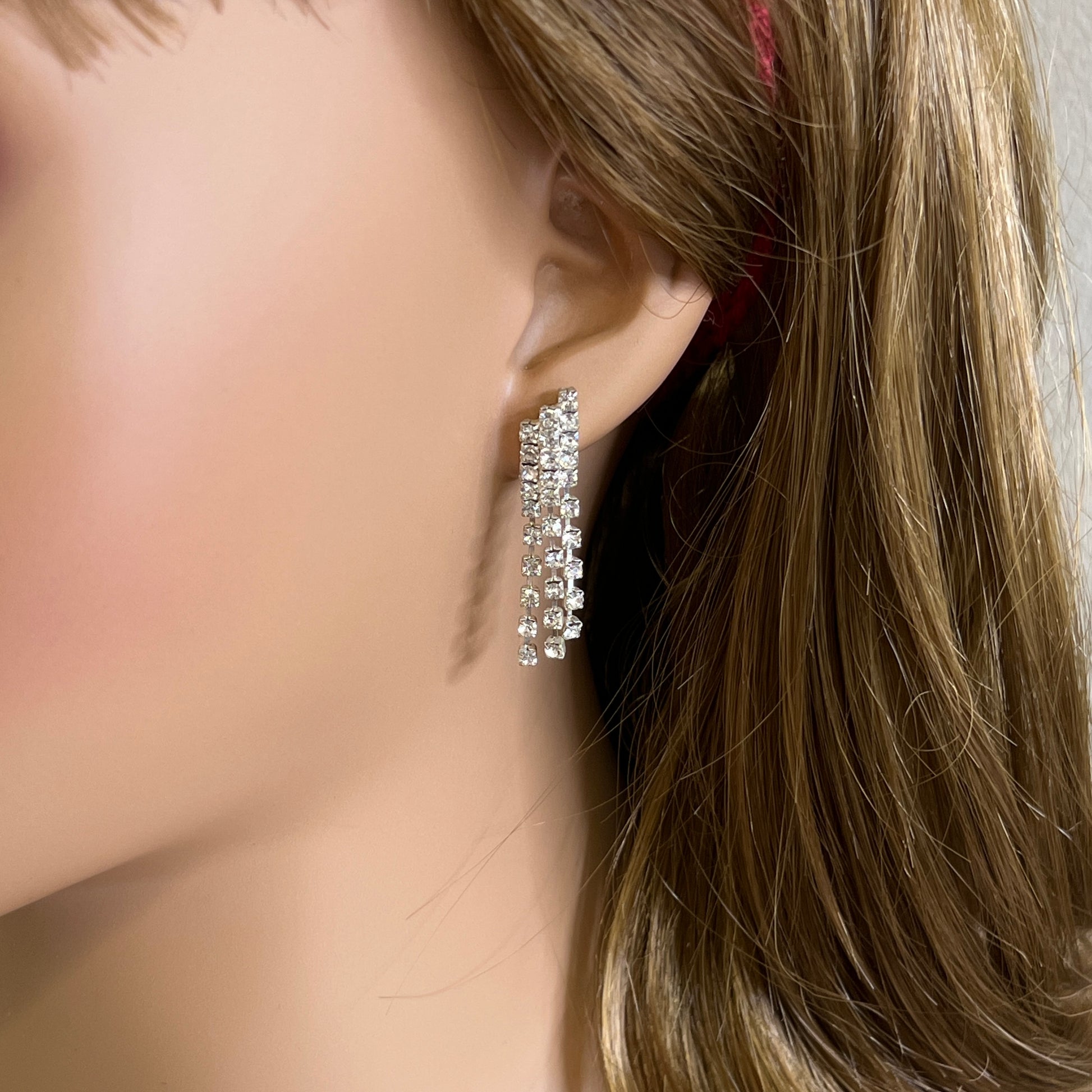 Close-up of silver-tone fringe earrings with prong-set crystals