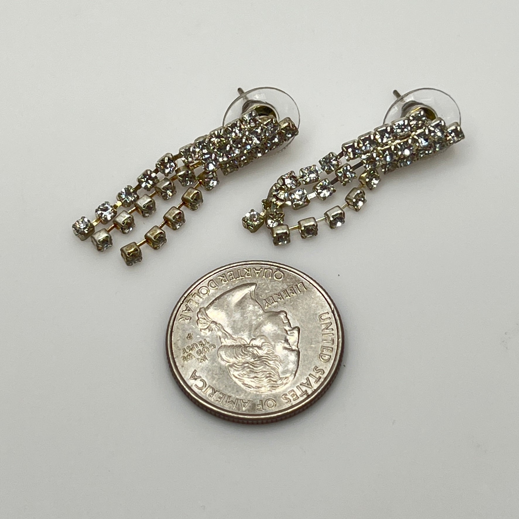 Close-up of silver-tone fringe earrings with prong-set crystals