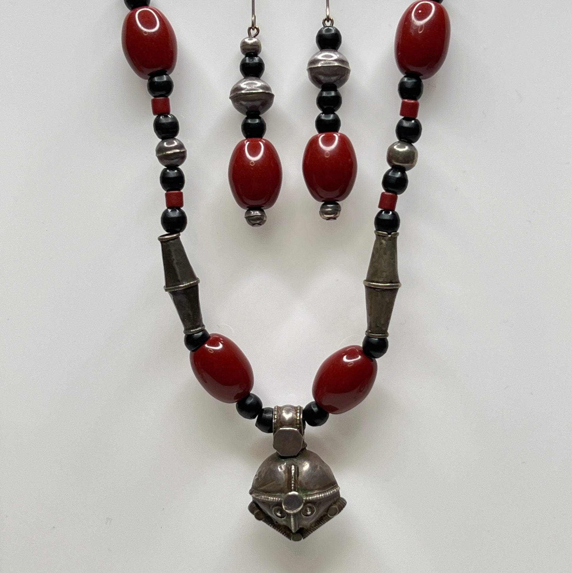 Beaded necklace and earrings with red, black, and silver beads on a white background