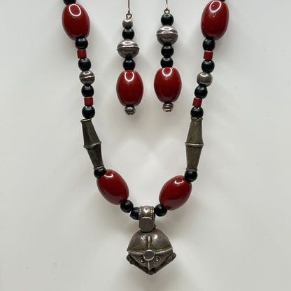 Beaded necklace and earrings with red, black, and silver beads on a white background
