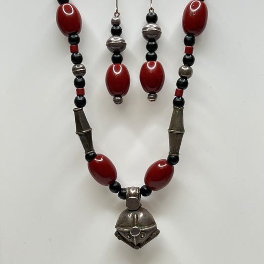 Beaded necklace and earrings with red, black, and silver beads on a white background
