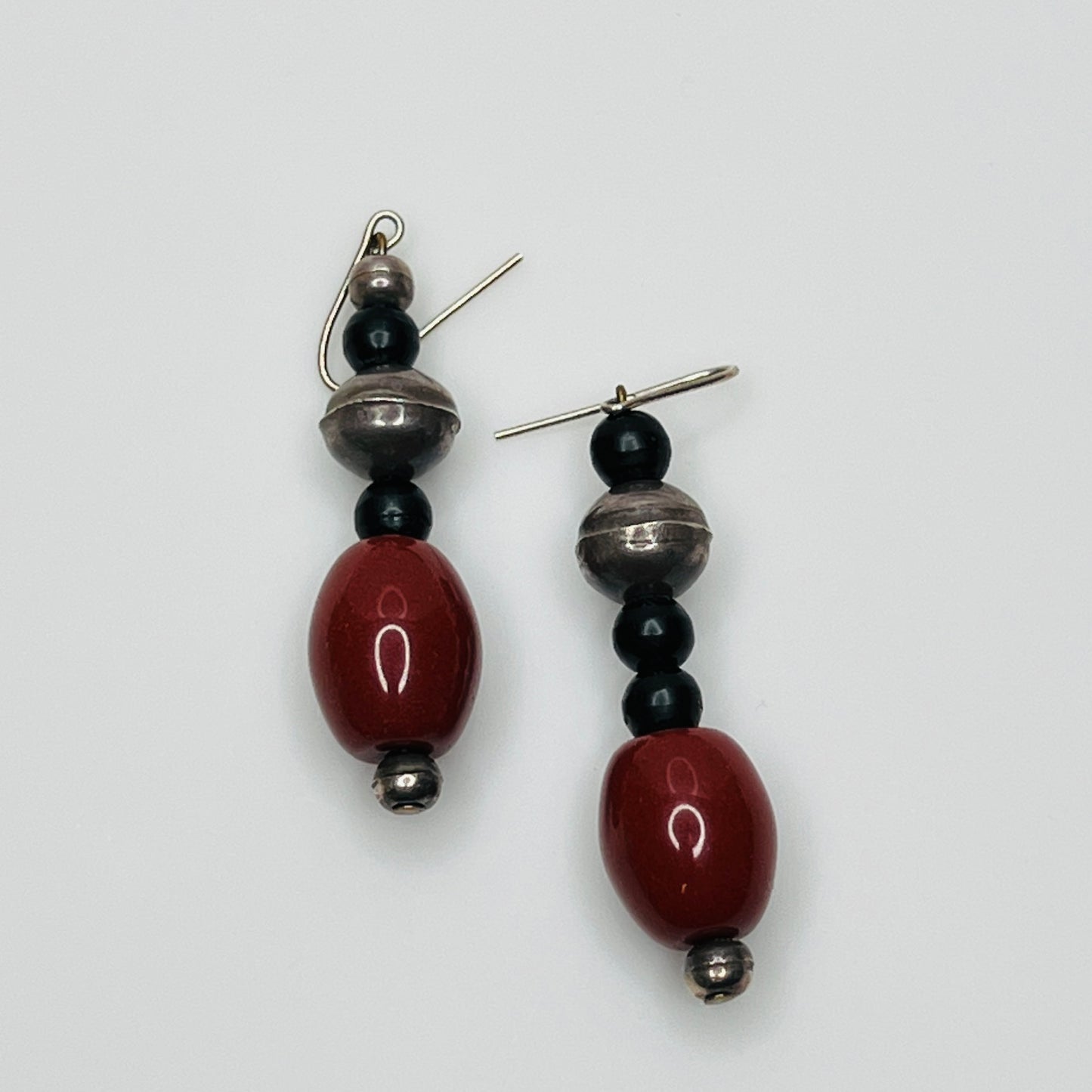 Pair of earrings with red, black, and silver beads on a white background