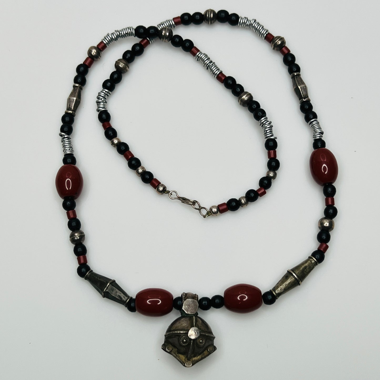 Beaded necklace with black, red, and silver beads on a white background