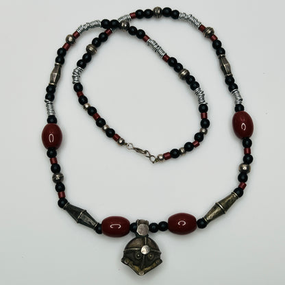 Beaded necklace with black, red, and silver beads on a white background
