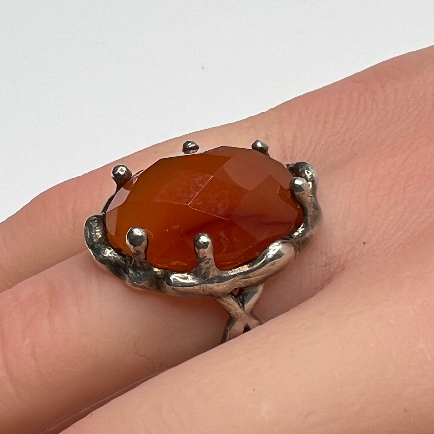 Vintage sterling silver ring with faceted oval orange carnelian in sculptural bezel setting