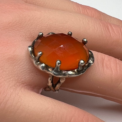 Vintage sterling silver ring with faceted oval orange carnelian in sculptural bezel setting