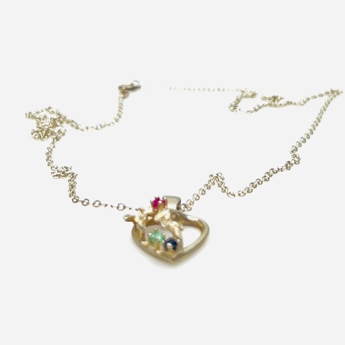 Side view of Avon sterling heart necklace with genuine ruby, emerald, and sapphire accents.