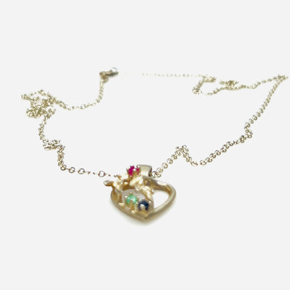 Side view of Avon sterling heart necklace with genuine ruby, emerald, and sapphire accents.