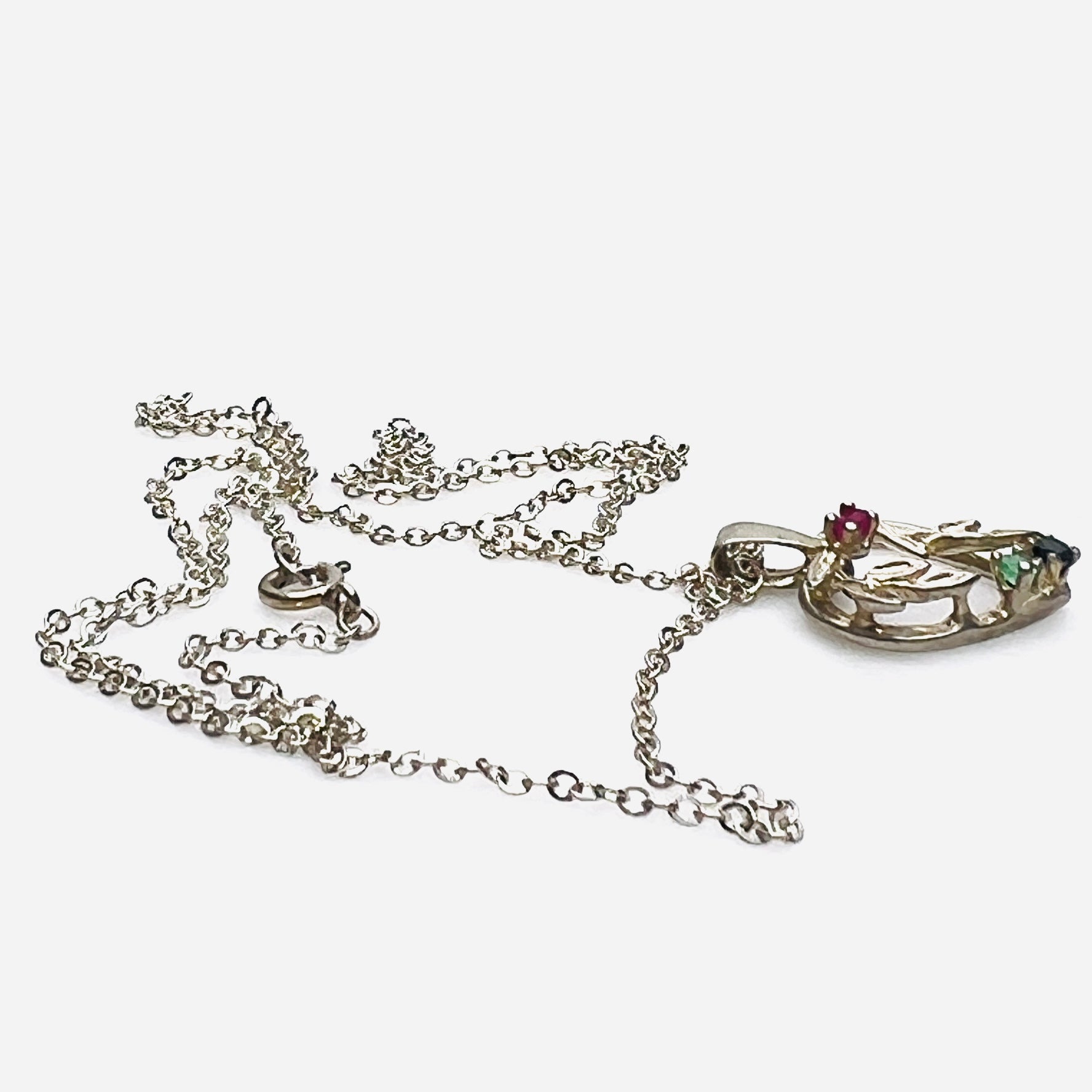 Side view of Avon sterling heart necklace with genuine ruby, emerald, and sapphire accents.