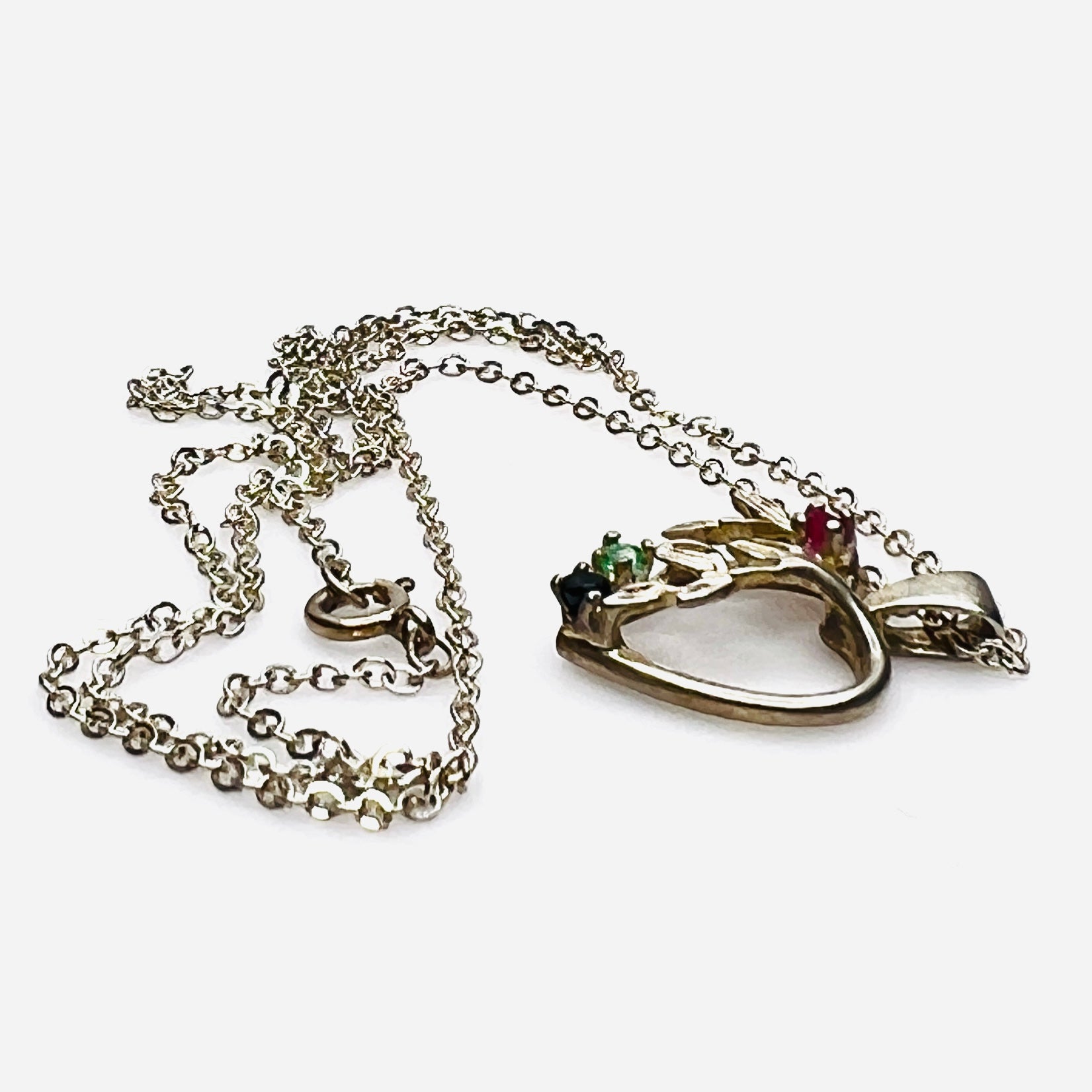 Side view of Avon sterling heart necklace with genuine ruby, emerald, and sapphire accents.