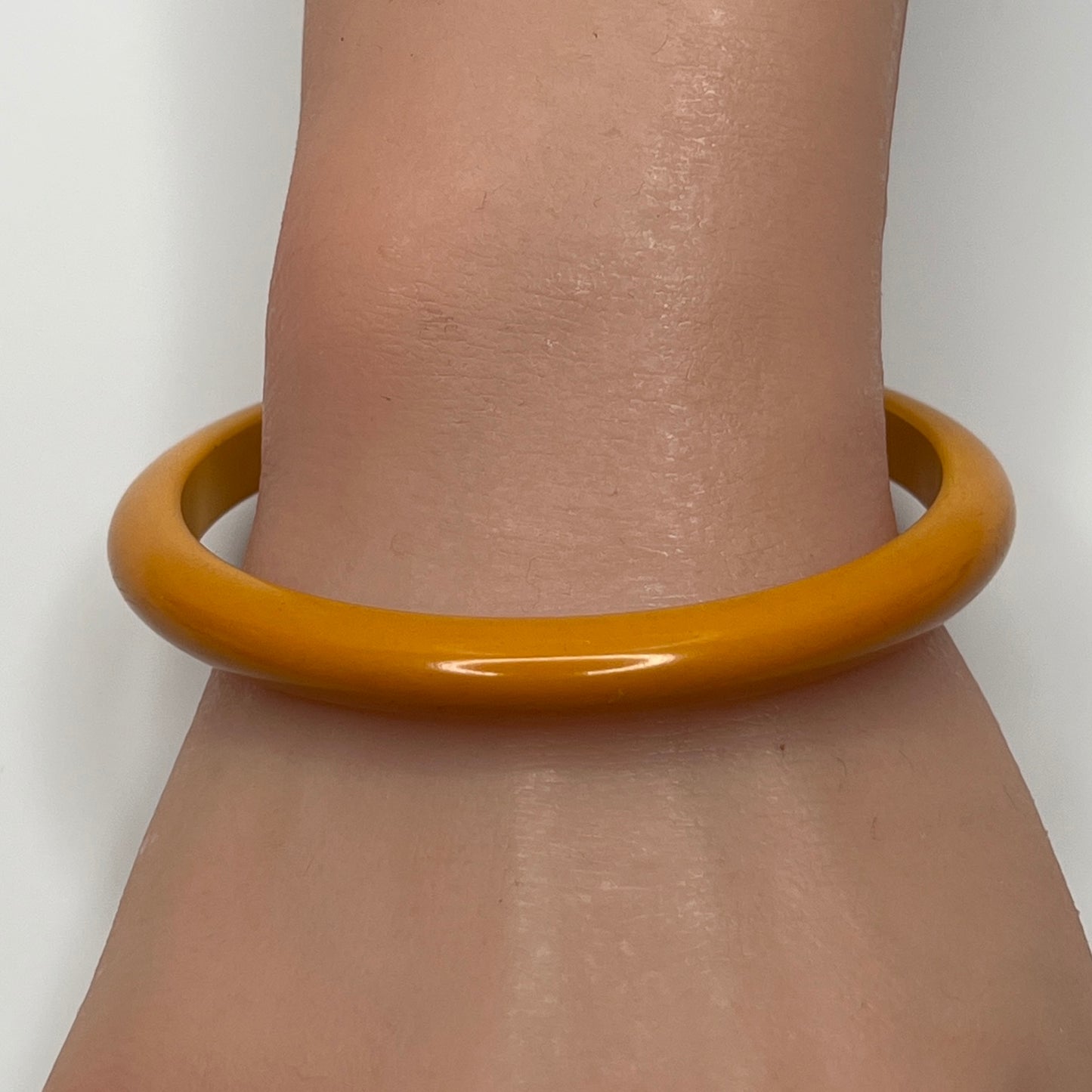 Butterscotch Bakelite bangle bracelet on wrist, slim vintage style