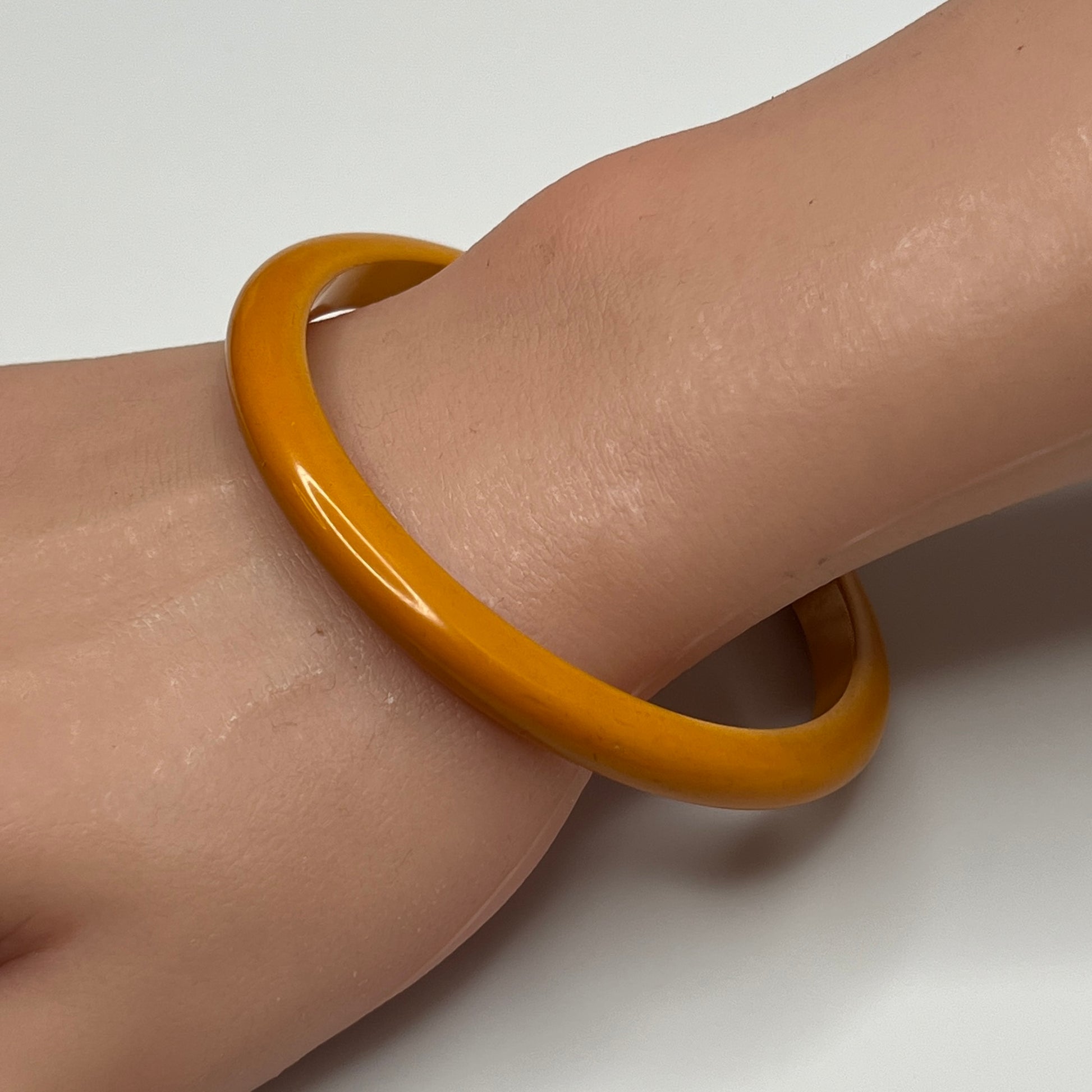 Butterscotch Bakelite bangle bracelet on wrist, slim vintage style