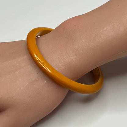 Butterscotch Bakelite bangle bracelet on wrist, slim vintage style