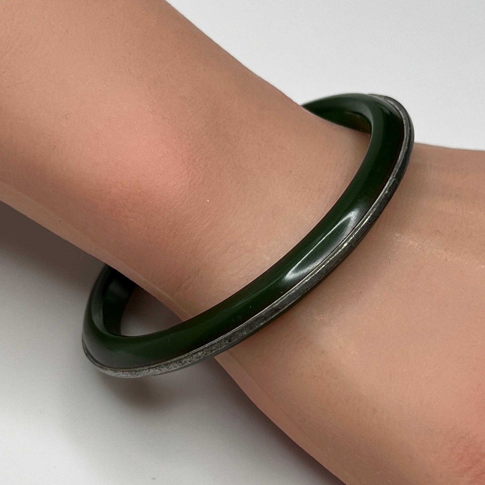 Vintage Bakelite bracelet on wrist showing glossy finish and silver channel