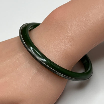 Vintage Bakelite bracelet on wrist showing glossy finish and silver channel