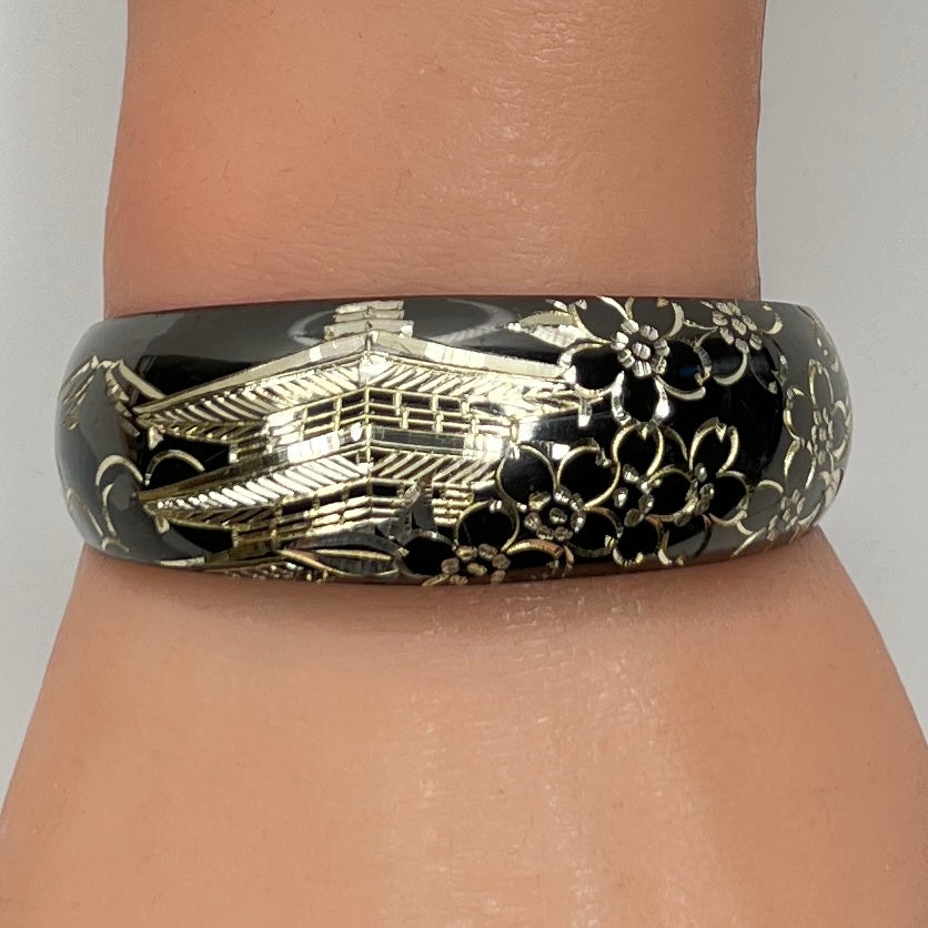Bracelet shown on wrist, highlighting engraved silver pagoda and blossoms